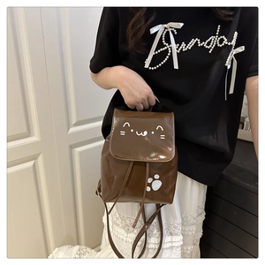 Detail of a mini brown patent leather backpack with cute white cat face and paw prints