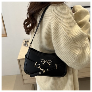 Détail du sac bandoulière en cuir noir mat avec boucle en métal et lanières à œillets