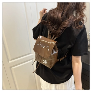 Detail of brown PU mini backpack with cartoon cat graphics on a female model