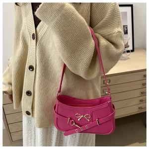 Détail du sac baguette rose rouge avec nœud en métal et ceinture sur un mannequin