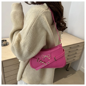 Gros plan du sac à bandoulière rose avec nœud métallique porté par un mannequin