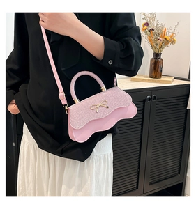 Dettaglio della borsa rosa con fiocco, base ondulata e finitura in tessuto glitterato
