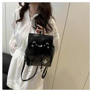 Close-up of a black glossy mini backpack featuring a cute white cat face on the flap