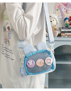 Detail of light blue bunny ear crossbody bag with cute badges and mesh pocket design
