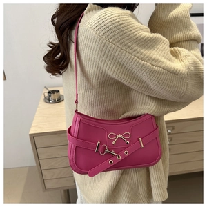 Détail du sac à bandoulière rose pêche en similicuir avec nœud doré et sangle métallique