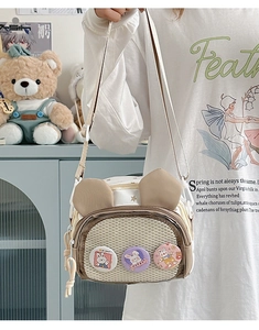 Detail of cute bunny ear crossbody bag with mesh pocket and three cartoon badges