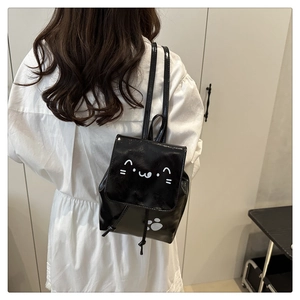 Mini sac à dos noir en similicuir avec motifs de chat porté par un mannequin en blanc