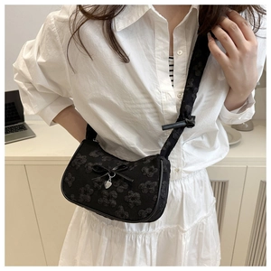 Detalle del bolso jacquard negro con lazo de cinta y colgante de corazón plata