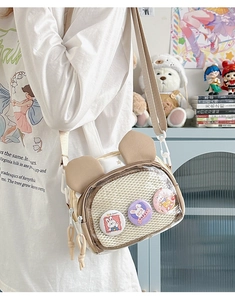 Detail view of cream canvas crossbody bag featuring 3 cute rabbit badges in clear mesh pocket