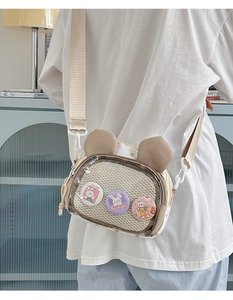 Detail of beige crossbody bag with bunny ears, mesh pocket and cute pins decoration