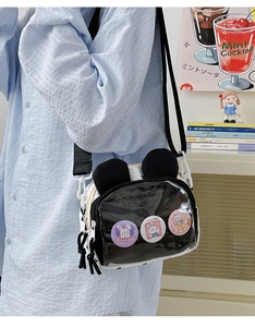 Detail of cute rabbit crossbody bag with clear window and cartoon pins on adjustable strap