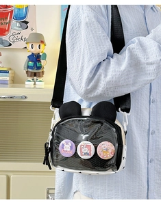 Detail view of transparent PVC pocket with cute rabbit badges on a white canvas crossbody bag