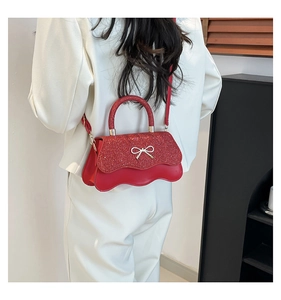 Dettaglio della patta glitterata rossa con fiocco argento e bordo ondulato della borsa