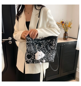 Detail view of graffiti tote bag with plush charm on a model in white blazer