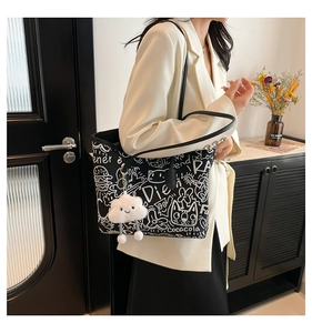 Detail of black graffiti tote bag with cloud charm and artistic pattern on shoulder