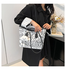 Side view of a white graffiti canvas tote bag with black strap and cloud plush charm