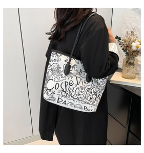 Detail view of white tote bag with black graffiti art and long shoulder straps