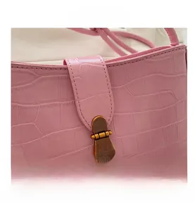 Macro detail of pink crocodile texture with retro gold metal buckle on shoulder bag