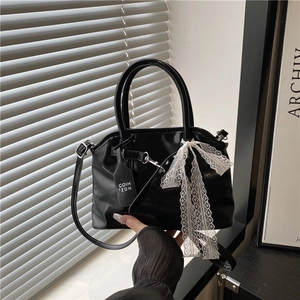 Détail du sac en similicuir noir orné d'un nœud en dentelle blanche et d'un pendentif