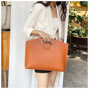 Détail du sac cabas orange vif avec poignée circulaire en métal argenté et fermoir magnétique