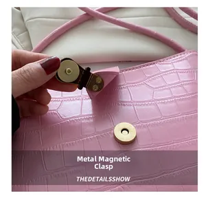 Detail of pink croc-embossed leather bag showing high-quality gold magnetic buckle closure