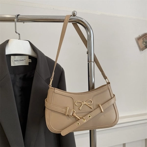 Sac baguette chic en similicuir beige avec nœud en métal sur fond de blazer gris