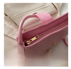 Detail view of pink crocodile-textured shoulder bag with gold metal zipper and smooth finish