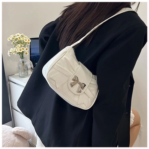 Close-up of white shoulder bag with metallic bow buckle and pleated patent finish