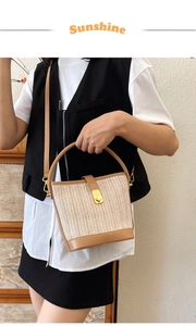 Close-up of beige woven straw bucket bag with leather handle and golden metal buckle