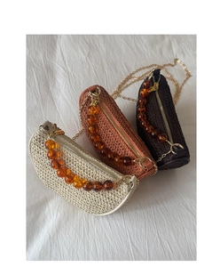 Detailed view of woven straw handbags in three colors with acrylic beaded handles
