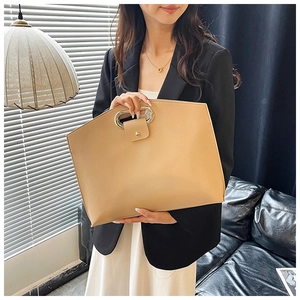 Gros plan sur sac d'ordinateur en cuir beige avec poignée métallique dans un bureau