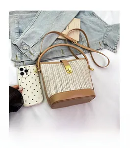 Detail of woven straw bucket bag with brown leather accents and gold twist lock closure