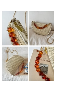 Detail of woven crescent bag with amber beads, golden chain, and metallic zipper