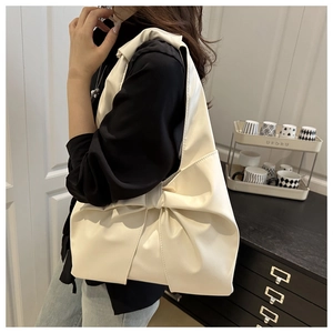 Close-up of cream white pleated shoulder bag with large bow and soft leather texture