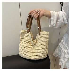 Detail der Strohtasche mit braunen Ledergriffen und goldenen Nietendetails