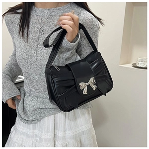 Détail du sac à bandoulière noir plissé avec un grand nœud en métal argenté