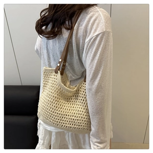 Dettaglio della trama all'uncinetto e tracolla in pelle marrone della borsa beige
