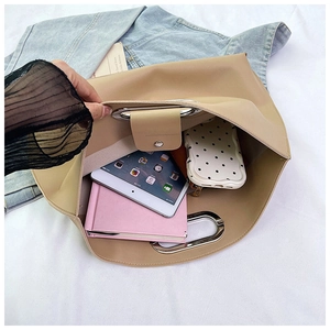 Détail de l'intérieur spacieux du sac d'affaires beige avec poignées métalliques rondes