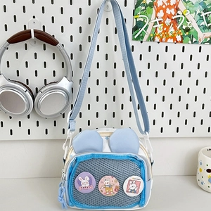 Cute blue rabbit ear crossbody bag with bunny badges on a white pegboard backdrop