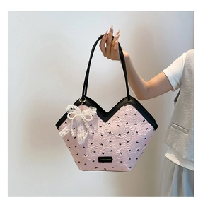 Detail of pink pleated fabric bucket bag with bow print and pearl lace charm accessory