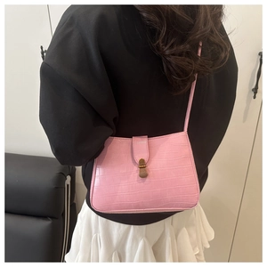Detail of pink faux crocodile texture bag with vintage gold buckle on model's shoulder