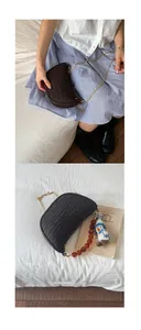 Detail of woven crescent bag with golden chain strap and plush penguin charm accessory