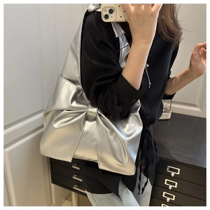 Macro view of the silver metallic bow-shaped shoulder bag featuring a mirrored finish