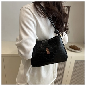 Detail of black crocodile embossed underarm bag with gold buckle and long shoulder strap