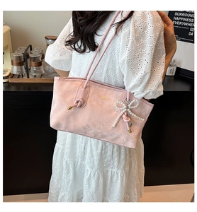 Pink tote bag with python pattern and pearl bow charm shown in a cozy cafe setting