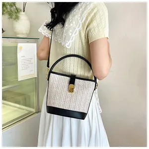 Chic woven bucket bag with leather base shown on a model in a cozy cafe setting
