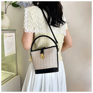 Detail of woven bucket bag featuring V-shaped texture and black leather strap with gold lock
