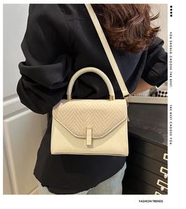 Minimalist beige small square handbag with woven texture and gold hardware detail on model