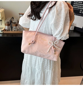Detail of pink faux leather tote bag featuring diamond quilt texture and pearl bow charm