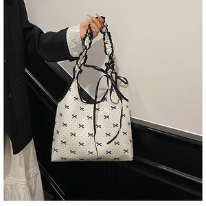Detail of white tote bag with black bows, polka dots, and ruffled shoulder straps